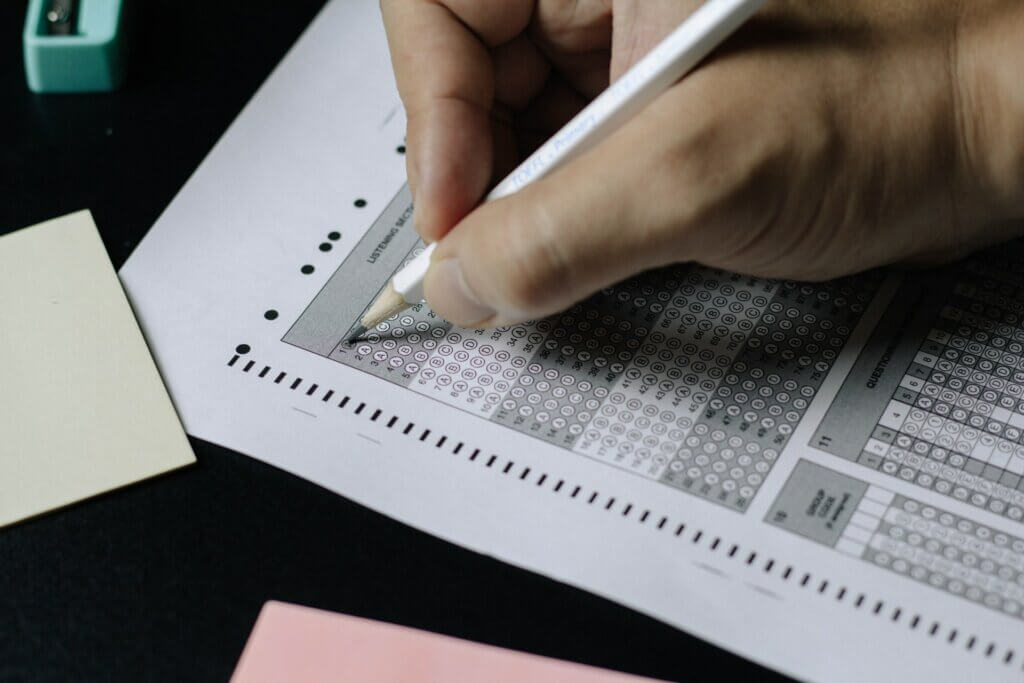 Close up of hand filling out a scantron test paper